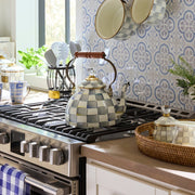 MacKenzie Childs | Sterling Check Tea Kettle, 3 QT on a stainless-steel range, surrounded by matching ceramic cookware and kitchen accessories in a sunlit, home-style kitchen.