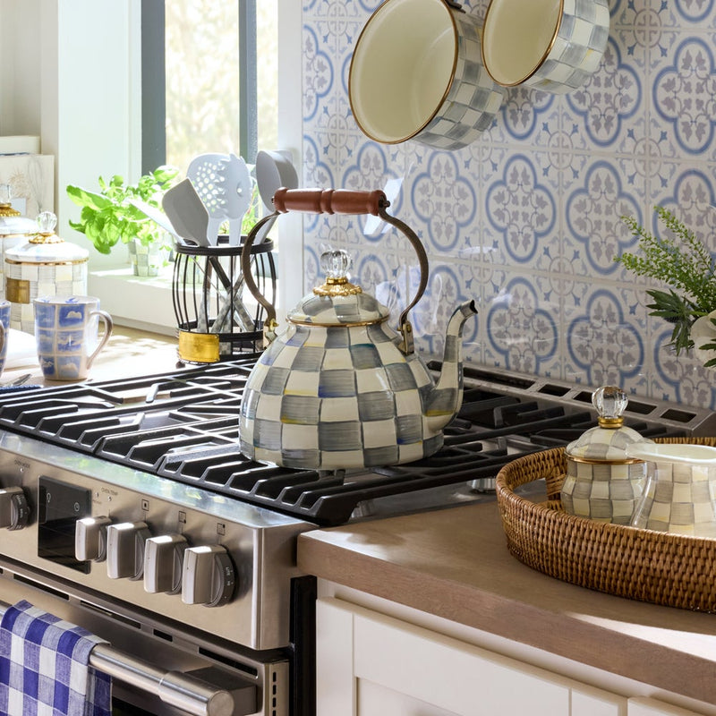 MacKenzie Childs | Sterling Check Tea Kettle, 3 QT on a stainless-steel range, surrounded by matching ceramic cookware and kitchen accessories in a sunlit, home-style kitchen.