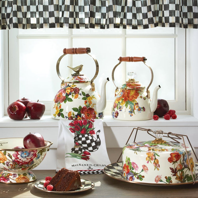 MacKenzie-Childs White Flower Market Large Colander on a homey windowsill, surrounded by hand-painted enamelware, apples, raspberries, and a checkered tea towel, reflecting kitchen charm.