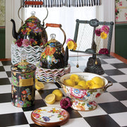 MacKenzie-Childs White Flower Market Large Colander filled with lemons and flowers, showcasing its floral design on a checkerboard table with matching kitchenware.