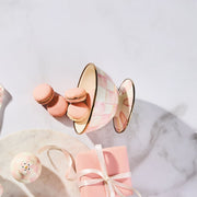 MacKenzie-Childs Rosy Check Ice Cream Dish displayed with pink macarons, checkered shaker, and gift box on a marble serving board.