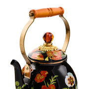 Mackenzie Childs | Poppy Tea Kettle, 2 QT. features a black enamel body with floral motifs, wood handle, brass fittings, and a decorative glass finial.
