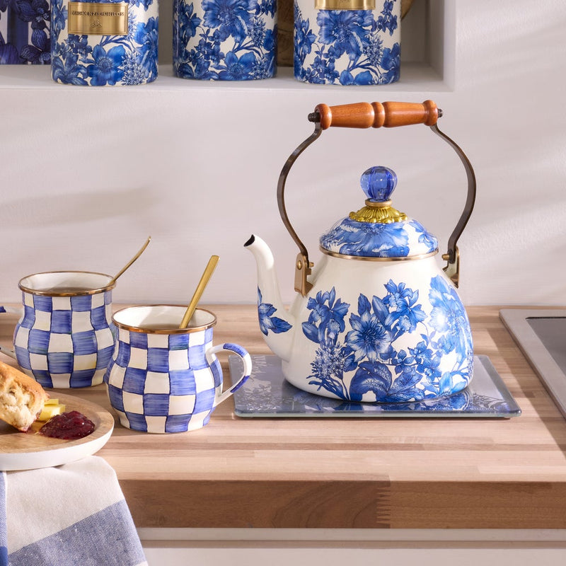 MacKenzie-Childs Royal English Garden 2 Quart Tea Kettle with floral blue pattern, brass-tone trim, and wooden handle on a kitchen countertop with matching mugs and scones.