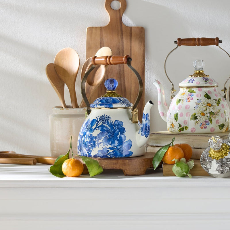 MacKenzie-Childs Royal English Garden 2 Quart Tea Kettle with blue floral motifs and wooden handle, displayed with tangerines and a matching sugar bowl on a white shelf.