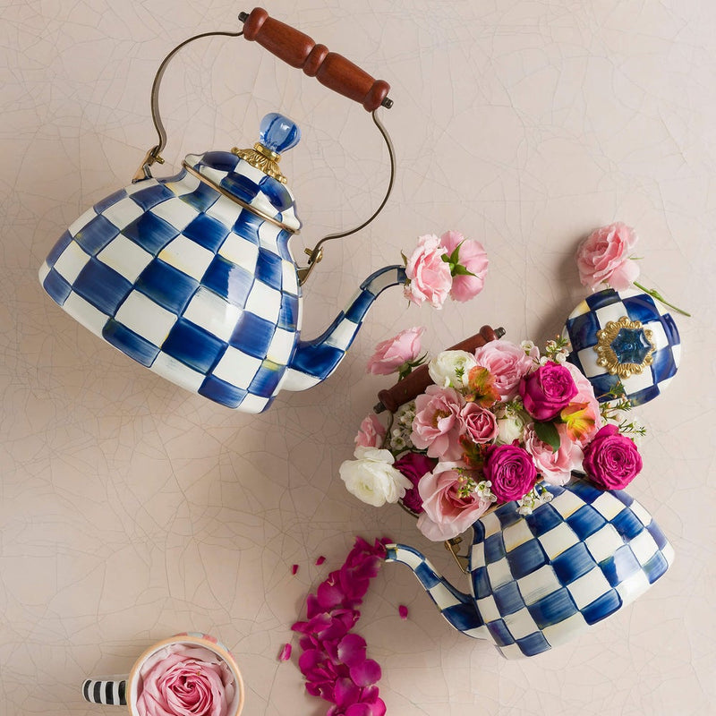 MacKenzie Childs | Royal Check Tea Kettle, 2 QT., displayed with pink rose petals and flowers, featuring blue-and-white checks, wood handle, brass-tone accents.