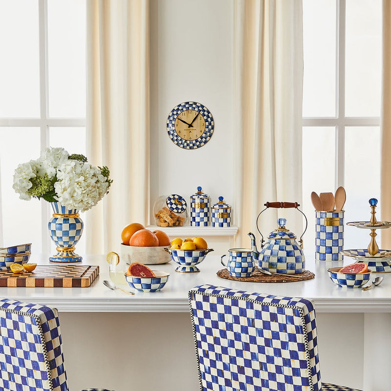 MacKenzie Childs | Royal Check Tea Kettle, 2 QT., sits on a blue-and-white checkered table, surrounded by matching serveware and vibrant fruits in a sunlit kitchen.