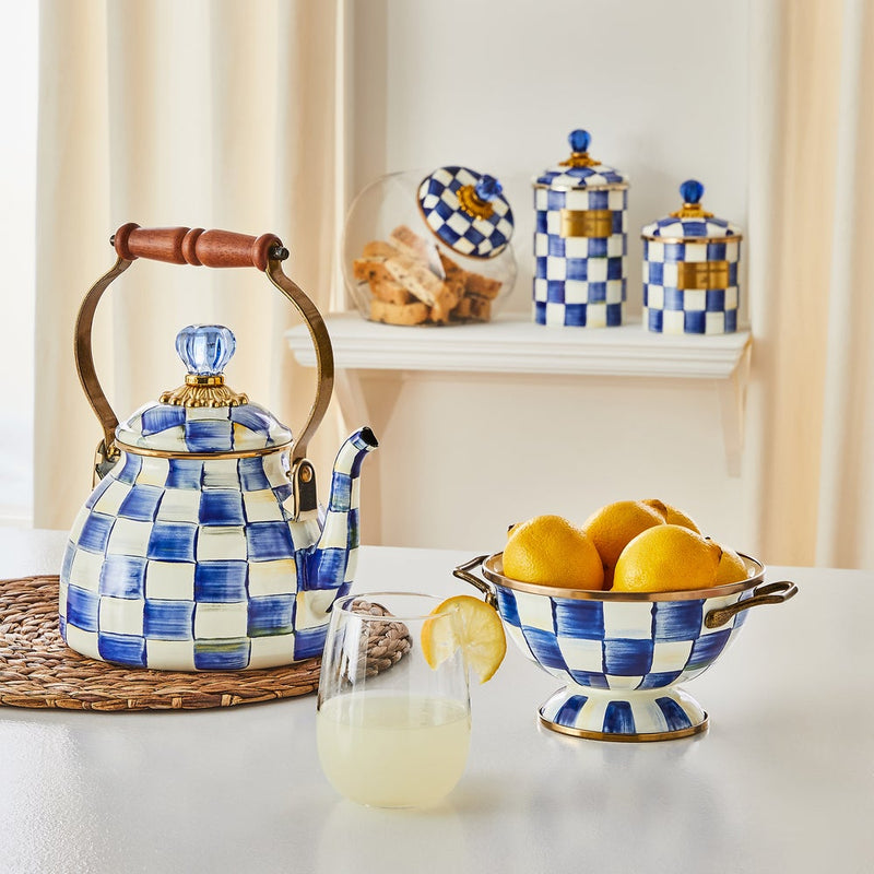 MacKenzie Childs | Royal Check Tea Kettle, 2 QT., with blue-and-white checks, wooden handle, and glass-knobbed lid, set on a kitchen table with matching porcelain accessories.