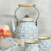 MacKenzie-Childs Sky Check Tea Kettle, 2 Qt, features a hand-painted blue and white check pattern with a brass-tone lid and wooden handle, perfect for cozy tea moments.