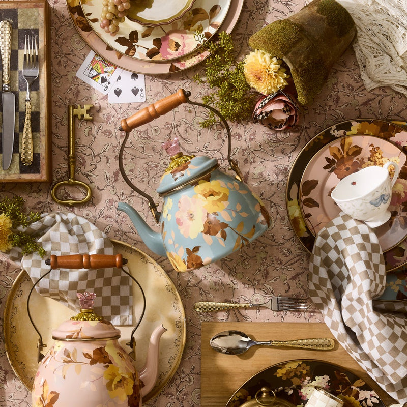 MacKenzie-Childs Wild Rose Slate Tea Kettle, 2 Qt, showcased amidst vintage floral teapots, gold flatware, and decorative objects on a patterned tablecloth.