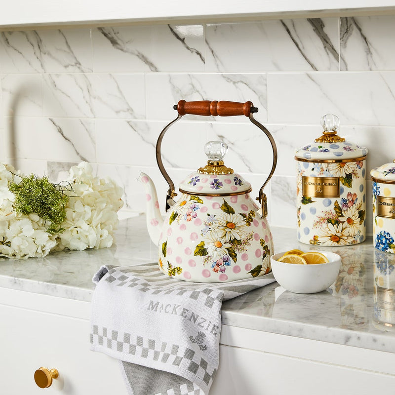 MacKenzie Childs | Wildflowers Pink Tea Kettle, 2 QT, with floral designs on a marble counter, surrounded by matching floral canisters, lemon slices, and hydrangeas.
