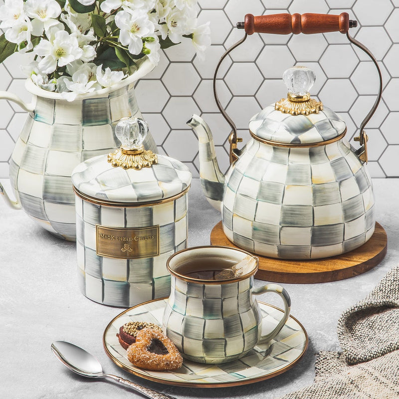 MacKenzie Childs | Sterling Check Tea Kettle, 2 QT., with a wooden handle and checkered pattern, elegantly displayed with matching ceramics and tea service elements.