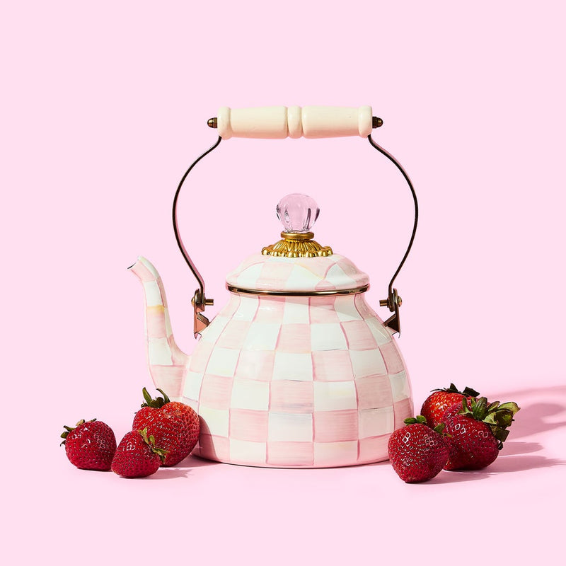 MacKenzie Childs | Rosy Check Tea Kettle, 2 QT: Ceramic teapot in a pink-and-white checkerboard pattern with brass accents, wooden handle, and surrounded by fresh strawberries.