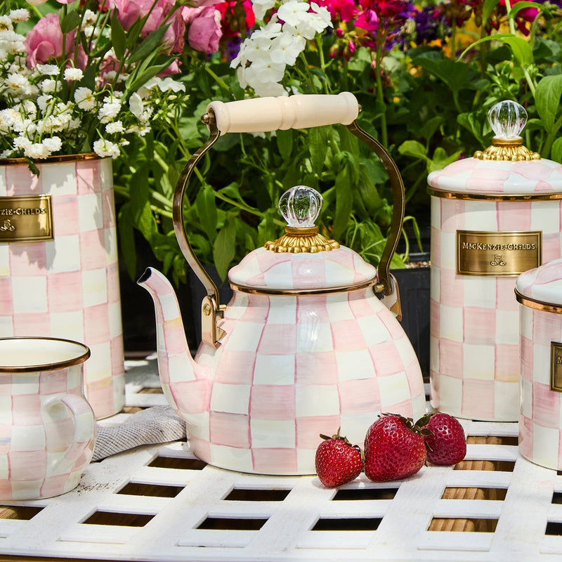 MacKenzie Childs | Rosy Check Tea Kettle, 2 QT, elegantly displayed with matching canisters and teacup, surrounded by strawberries and flowers on a garden-themed tabletop.