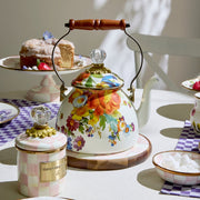 MacKenzie Childs | White Flower Market 2 Quart Tea Kettle with floral design, glass knob, and wood handle, set amid afternoon tea essentials on a tablecloth.