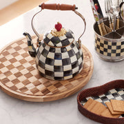MacKenzie Childs | Courtly Check 2 Quart Tea Kettle on a tray with kitchen utensils; features hand-painted checks, wood handle, and carved lid bead.
