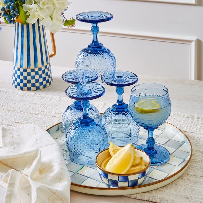 MacKenzie-Childs Sterling Check Round Tray with blue goblets and lemon wedges, styled for cocktail hour, highlighting its hand-painted design and versatile use for serving.