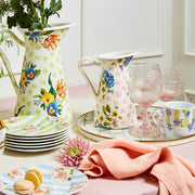 MacKenzie-Childs Sterling Check Round Tray with pink-tinted goblets, floral teacup, and ceramic pitchers, creating a pastel-themed spring tablescape with macarons and fresh flowers.