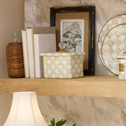 MacKenzie-Childs Mocha Check Recipe Box on a wooden shelf with glass knob, surrounded by home décor: wicker bottle, books, botanical print, and woven container.