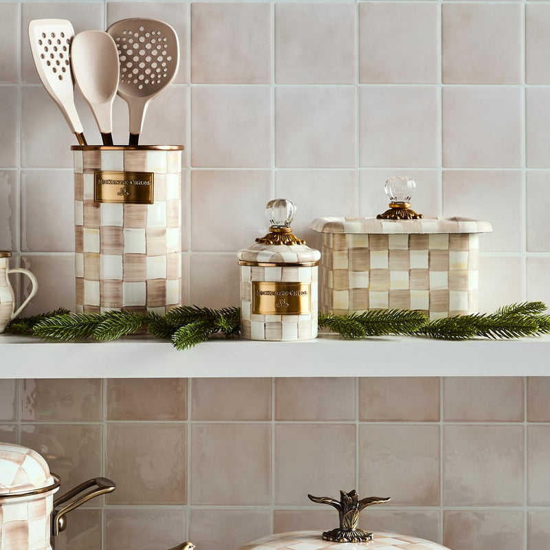 MacKenzie-Childs Mocha Check Recipe Box with glass knob and brass accents, displayed with matching utensils and decorative evergreens on a kitchen shelf.