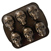 Nordic Ware Skull Cakelet Pan with six skull-shaped cavities, ideal for baking detailed mini skull cakes or molding spooky treats, perfect for Halloween gatherings.