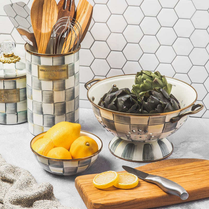 MacKenzie Childs Sterling Check Utensil Holder filled with wooden utensils on a styled kitchen countertop, featuring matching accessories with a hand-painted checkerboard pattern and artichokes.