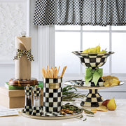 MacKenzie Childs | Courtly Check Utensil Holder on a checkerboard tray with matching serveware, filled with breadsticks, surrounded by styled pears, cheese, and greenery.