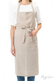Woman wearing MagicLinen - Charcoal Grey Linen Bib Apron with Pockets, showcasing a durable and stylish unisex design ideal for cooking and gardening.