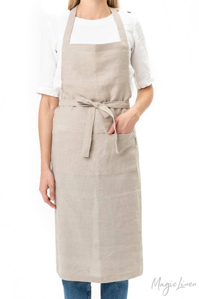 Woman wearing MagicLinen - Charcoal Grey Linen Bib Apron with Pockets, showcasing a durable and stylish unisex design ideal for cooking and gardening.