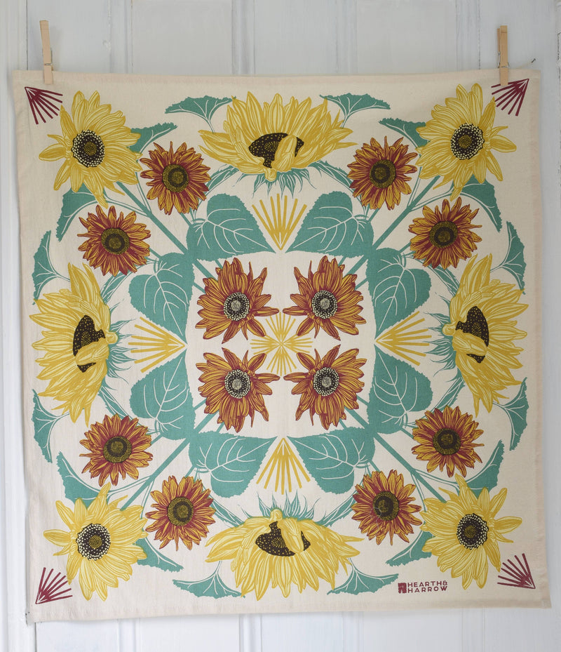 Hearth and Harrow - Sunflower Tea Towel - Organic Cotton - Oversized 30 x 30, featuring a sunflower pattern with teal leaves, hung with clothespins.