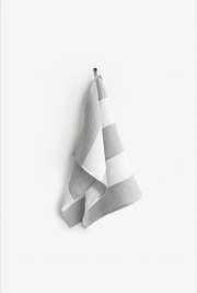 Striped linen tea towel with loop hanging on a hook, showcasing its practical design and zero-waste craftsmanship by MagicLinen, ideal for an eco-friendly kitchen.