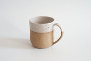 RachaelPots - 12 Oz Original Mug: Sage, hand-thrown ceramic mug with a speckled tan base and white glaze, featuring a thumb rest handle, perfect for beverages.