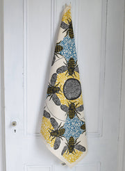 Hearth and Harrow - Honeybee Tea Towel - Organic Cotton - Oversized 30x30, featuring detailed bee motifs on honeycomb, hangs from a wooden door, showcasing its vintage-inspired design.