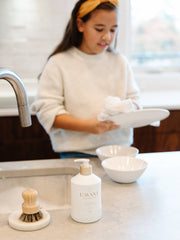 L'AVANT Collective - Fresh Linen High Performing Dish Soap in a matte white bottle held by a girl, showcasing its modern design and plant-based formula.