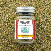 Burlap & Barrel - Herbes de Provence - Single Origin Spice & Seasoning Blend: 0.8 oz glass jar with metal lid, set against a backdrop of loose herbs.