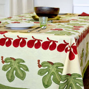 Couleur Nature - Fig Red & Green tablecloth with fig motifs adorns a dining table set with a plate, tumbler, utensils, and wooden bowls.