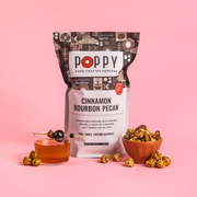 Poppy Hand-Crafted Popcorn - Cinnamon Bourbon Pecan flavor, featured with a garnished bourbon drink and a bowl of popcorn, embodies Southern-inspired gourmet snacking.