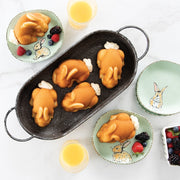 Nordic Ware | Baby Bunny Cake Pan showcasing adorable bunny-shaped cakes, surrounded by plates of fruit and glasses of orange juice, perfect for delightful baking experiences.