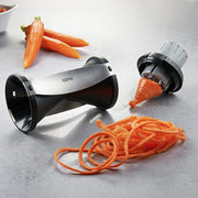GEFU Spiral Slicer on a table, surrounded by fresh carrots, ideal for creating spiral vegetable dishes in your kitchen.