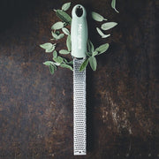 Microplane | Premium Zester, Grater - Sage Green with stainless-steel blade, surrounded by fresh sage leaves on a dark surface, ideal for versatile grating tasks.