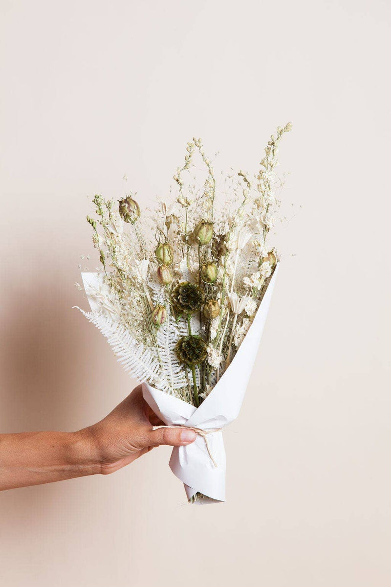Idlewild Floral Co. - Sage Small Field Bouquet features dried flowers wrapped in white paper, ideal for a rustic touch in a 4-6 vase.