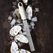 Microplane Premium Zester, Grater - Cashmere Beige on crushed ice with oyster shells, highlighting its fine rasp for effortless zesting and grating in culinary settings.