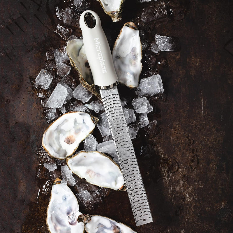 Microplane Premium Zester, Grater - Cashmere Beige on crushed ice with oyster shells, highlighting its fine rasp for effortless zesting and grating in culinary settings.