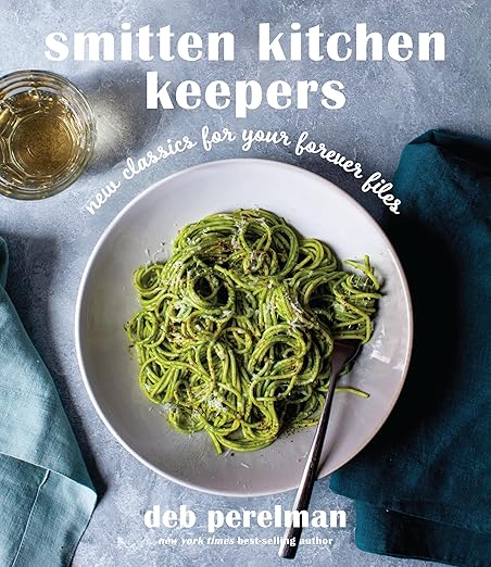 Cover of Smitten Kitchen Keepers: New Classics for Your Forever Files cookbook, featuring a bowl of green pesto spaghetti, by Deb Perelman, renowned food blogger and author.