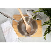 Heritage Steel 2 quart titanium saucier with lid and wooden spoon on a cutting board, ideal for cooking