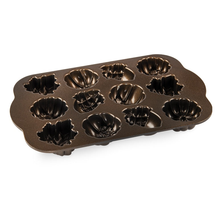 Nordic Ware | Autumn Delights Cakelet Pan featuring a design with holes, ideal for baking 12 charming acorn, leaf, and pumpkin-shaped cakelets, perfect for festive gatherings.