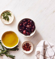 Kosterina - Spicy Kalamata Olives in bowls with olive oil and herbs, showcasing a gourmet blend perfect for salads or snacking.
