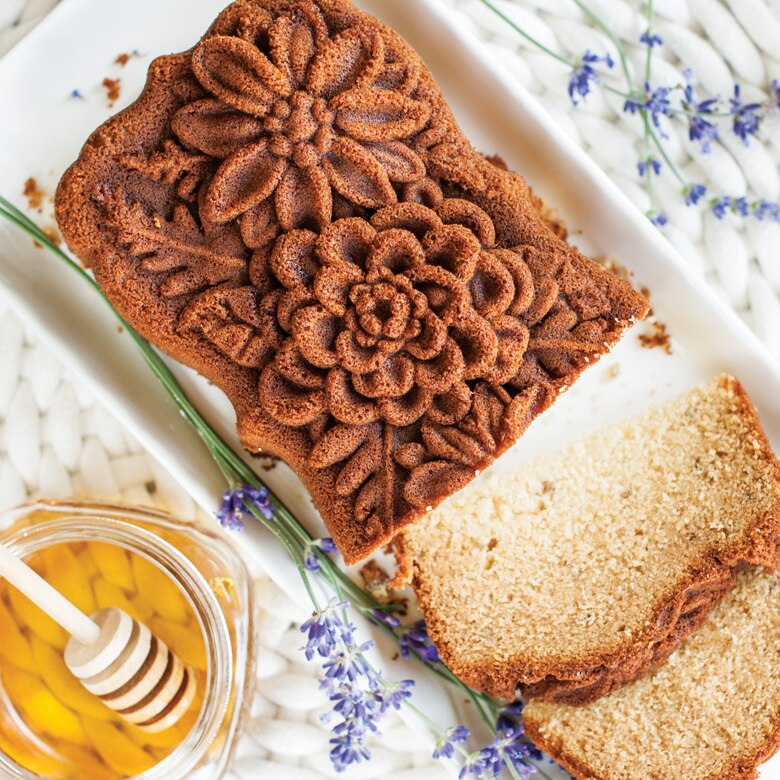 Nordic Ware | Wildflower Loaf Pan showcasing a detailed floral bread design, accompanied by honey, emphasizing the pan's nature-inspired elegance and nonstick baking perfection.