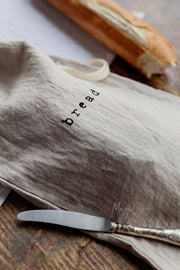 MagicLinen - Printed linen bread bag with bread logo, alongside a knife and loaf, perfect for keeping bread fresh, sold at Athens Cooks kitchen store.