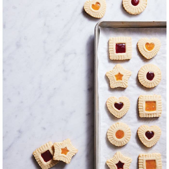 Assorted jam-filled shortbread cookies showcase the HIC - Harold Import Co. - King Arthur Thumbprint Cookie Cutters 4-Piece Set on a parchment-lined baking sheet.