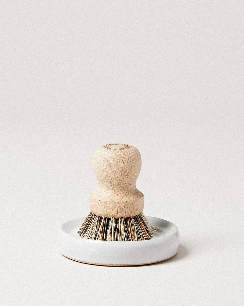 Farmhouse Pottery - Laurel Pot Brush Set: A hand-held scrub brush with a wooden handle and natural bristles, in a white ceramic dish, ideal for organized kitchen cleaning.